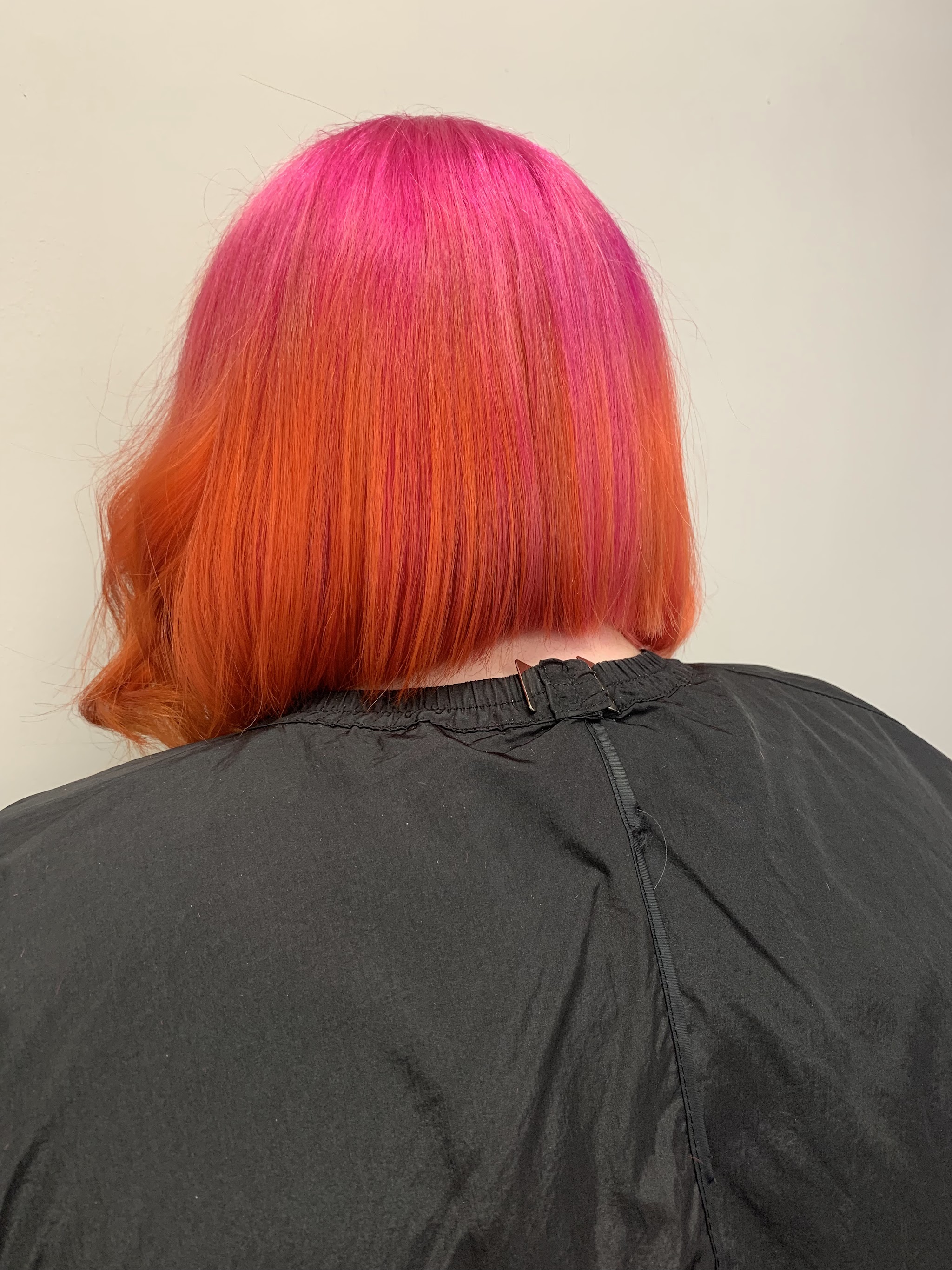 A vivid pink to orange colour on a bob, finished at the salon