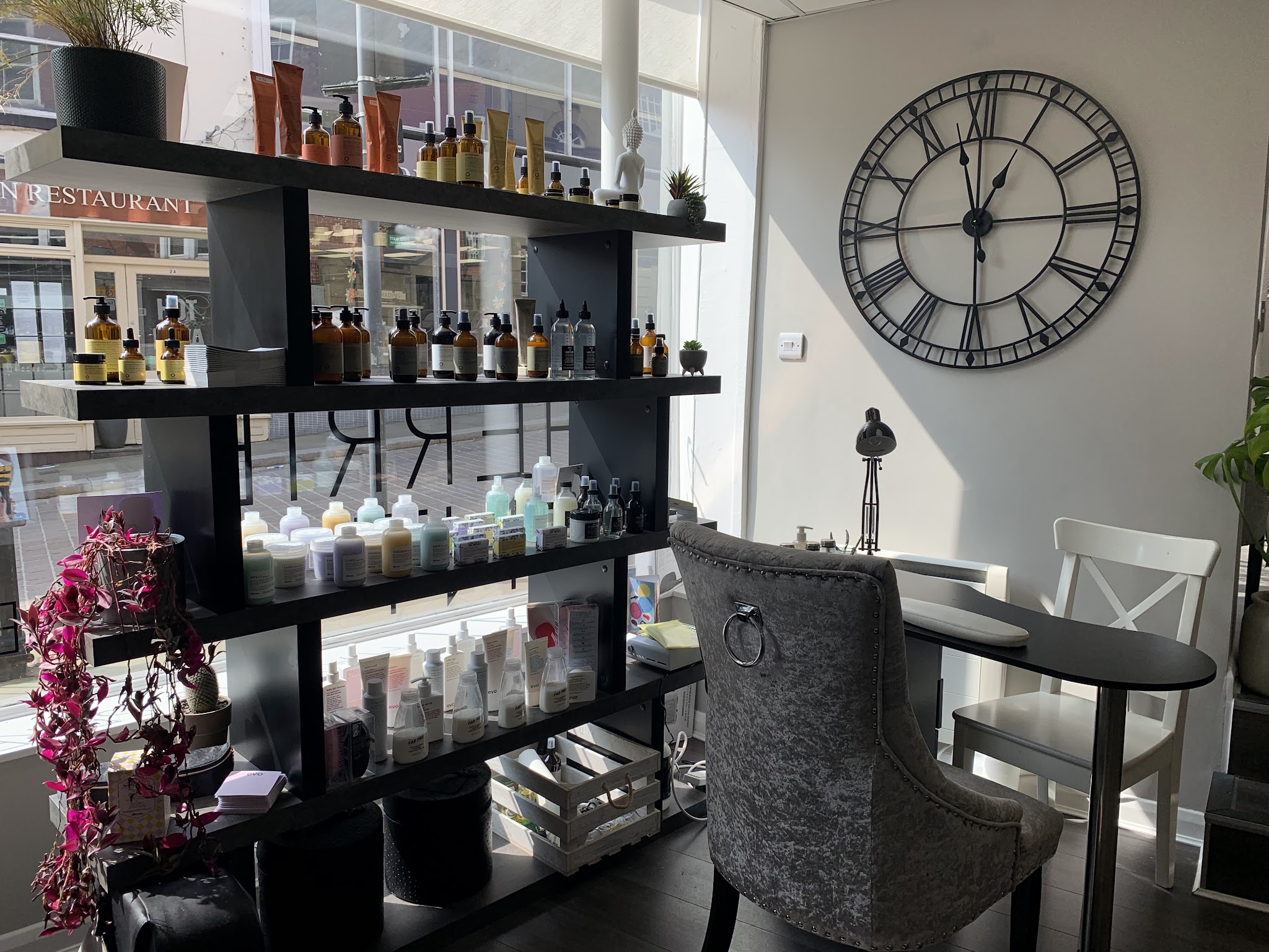 The retail wall with hair products, a large Roman numeral clock and a nail station